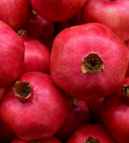 A vibrant close-up image of fresh ripe pomegranates displaying their natural red hue.